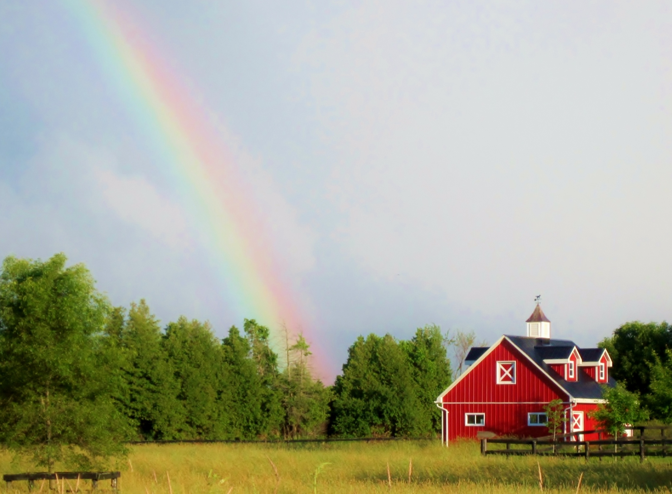 barn with rainbow in sky behind it