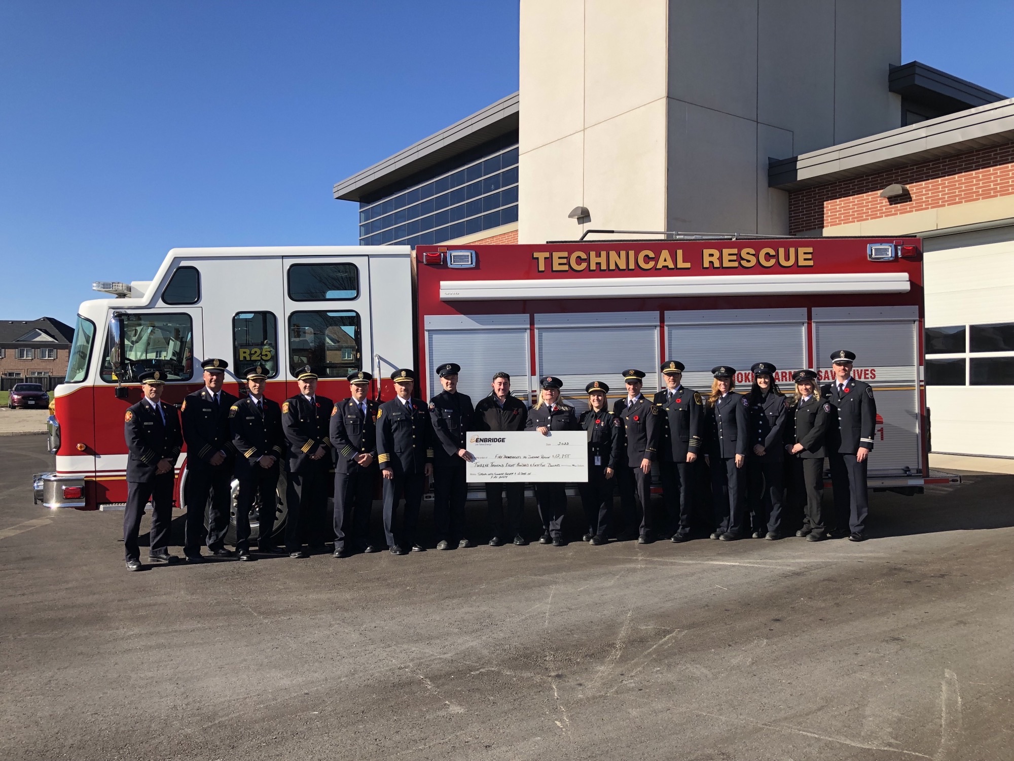 Picture of fire department representatives holding cheque from Enbridge in front of a fire truck