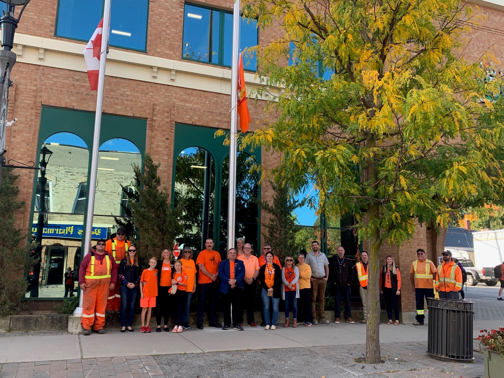 Council and Staff outside of Municipal building with Canadian Flag and Indigenous Flaf at half mast