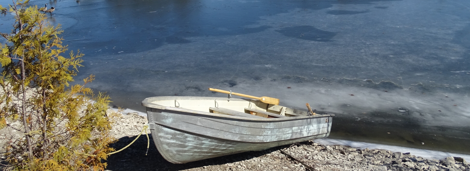 Boat on the shore of a thawing just barely icy lake