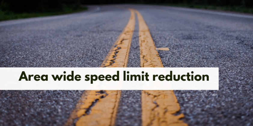 A photo of a road with a banner reading Area wide speed limit reduction in The Township of Brock.